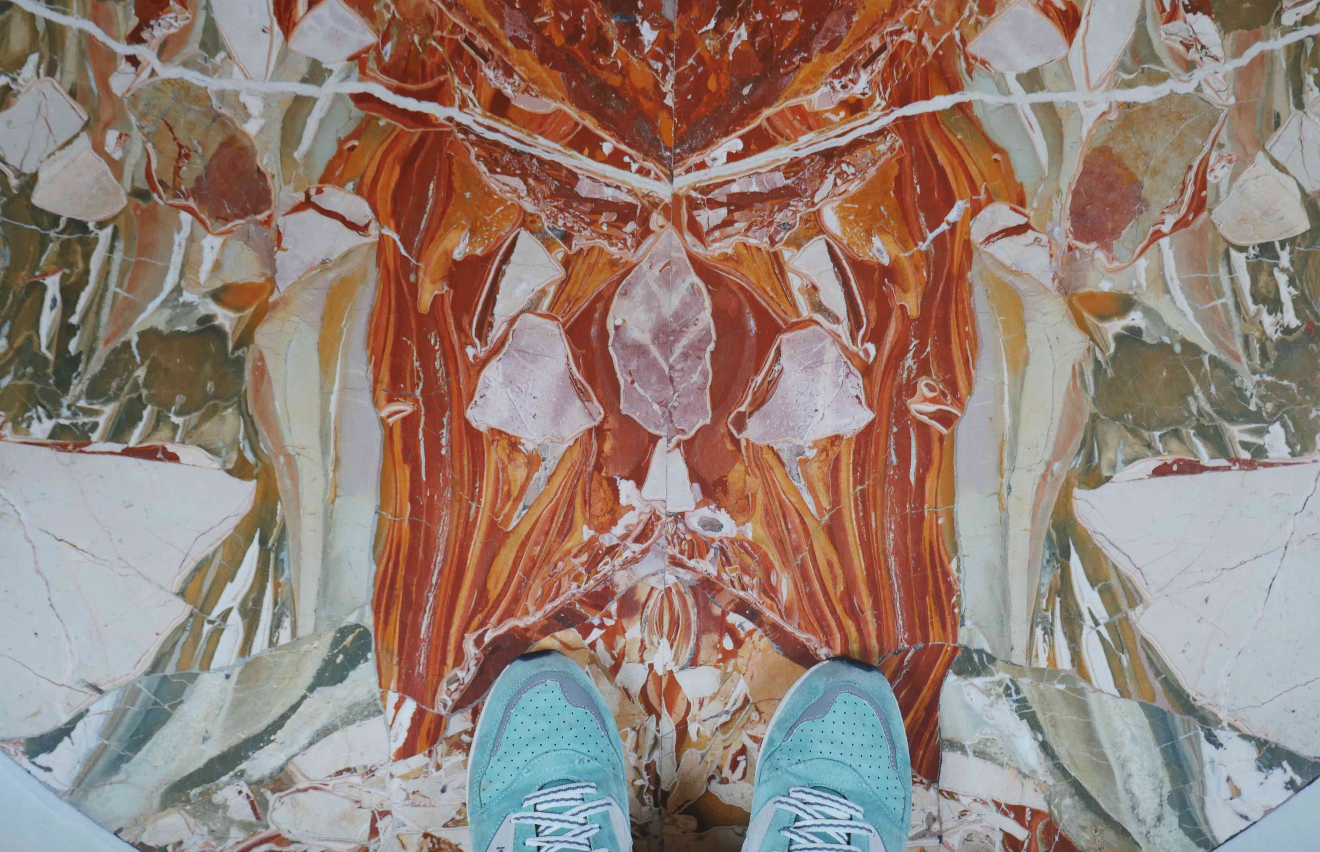 Turquoise shoes on a striated white, grey, and coral stone floor.